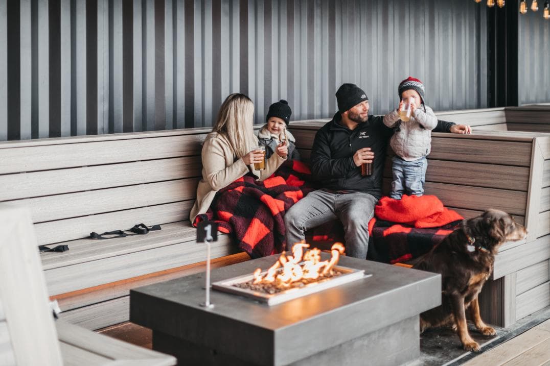 family enjoying a meal at an outdoor firepit red bird brewing kelowna